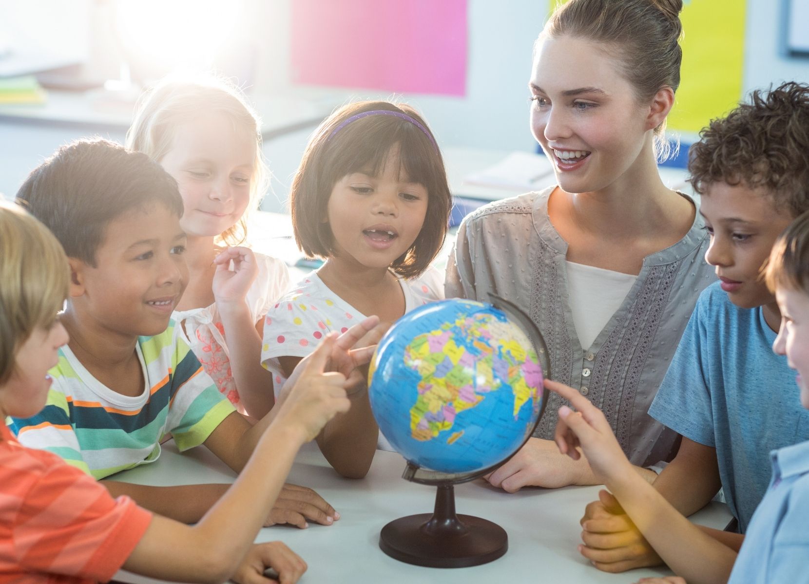 Een docent met kinderen rond een wereldbol